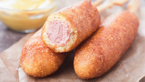 Esse hot dog no palito é ótimo para várias ocasiões. Para festa infantil, festinha em casa, reunião com amigos...Ele agrada a todos que adoram salsicha e um aperitivo rapidinho. O corn dog é titipcamente americano, mas nós, como bons braisleiros amantes de cachorro quente, servimos esse aperitivo com um gostinho bem abrasileirado, e ainda usamos alguns acompanhamentos especiais que são a nossa cara. O hot dog no palito nada mais é que a nossa queridinha salsicha, envolta em uma massa a base de fubá e farinha, que depois de frita, trará a deliciosa crocância do Corn Dog. Faça vários hot dogs no palito, convide a galera e aproveitem, e já guardem essa receita para as festas juninas, sem duvida ela será uma ótima opção para competir com o cachorro quente.