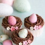 Aqui está uma receita fácil de cupcakes de Páscoa com ninho de buttercream de chocolate, recheados com mini ovos.