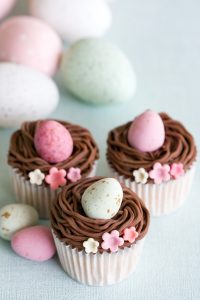 Aqui está uma receita fácil de cupcakes de Páscoa com ninho de buttercream de chocolate, recheados com mini ovos.