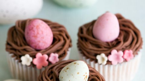 Aqui está uma receita fácil de cupcakes de Páscoa com ninho de buttercream de chocolate, recheados com mini ovos.